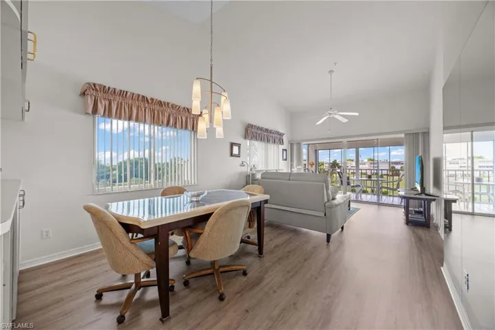 Dining area featuring high vaulted ceiling, ceiling fan, light wood-style flooring, and a chandelier
