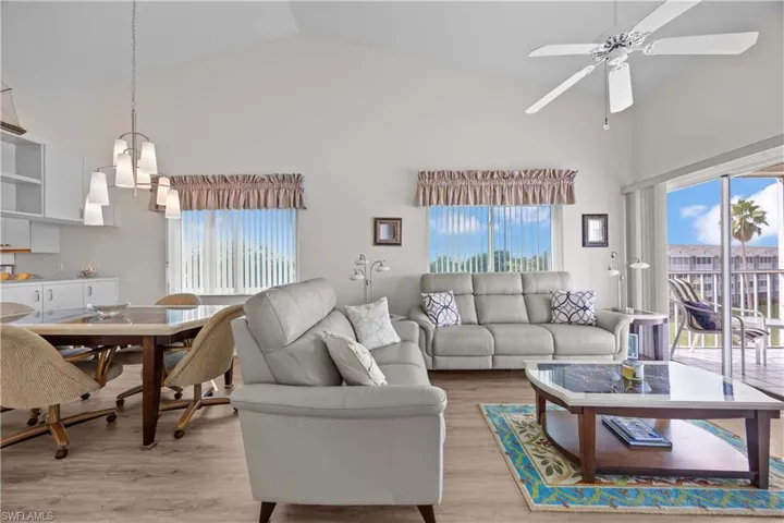 Living room featuring high vaulted ceiling, plenty of natural light, wood finished floors, and ceiling fan