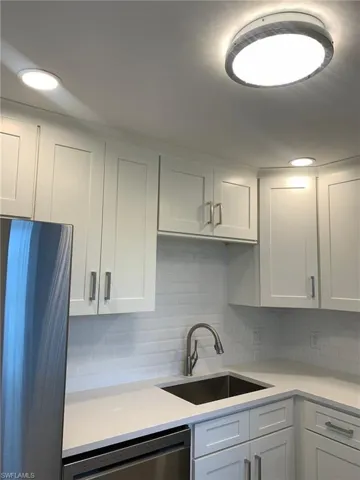 Kitchen featuring white cabinetry, stainless steel appliances, decorative backsplash, and recessed lighting