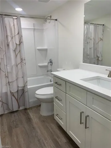 Bathroom with vanity, dark wood-type flooring, and shower / tub combo with curtain