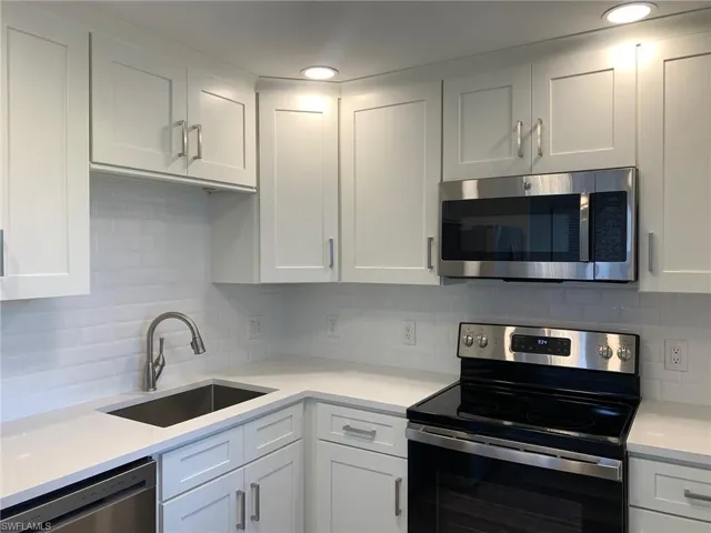 Kitchen featuring stainless steel appliances, white cabinets, tasteful backsplash, recessed lighting, and light stone counters