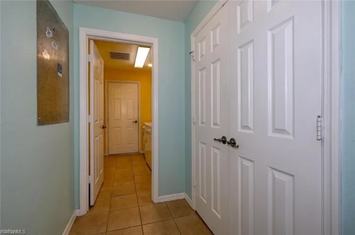 Interior hallway with light blue walls and neutral tile flooring