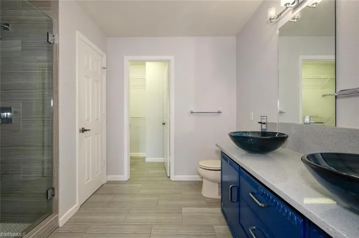 Bathroom featuring a dual vessel sink vanity with a light-colored countertop and vibrant blue cabinetry