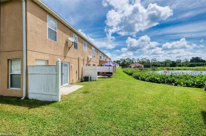 Expansive lawn area bordering a tranquil body of water, featuring a private patio space