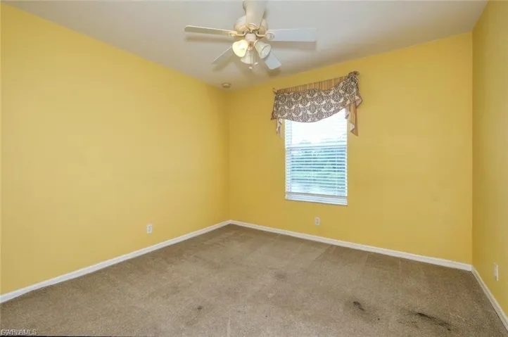Carpeted room featuring a ceiling fan, a window with blinds, and decorative valance