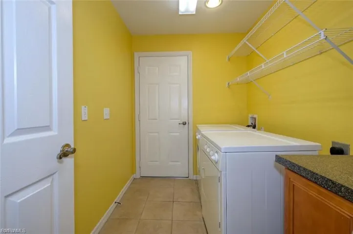Laundry room with tile flooring and bright yellow walls