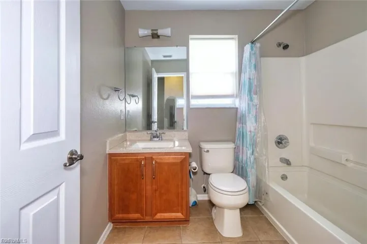 Bathroom featuring a wood-finish vanity with a light-toned countertop, a white rectangular sink, and a chrome faucet