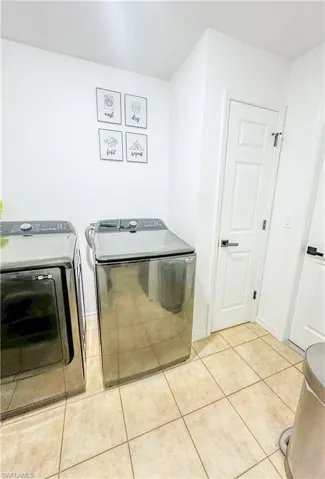 Laundry room featuring washer and dryer and light tile patterned floors