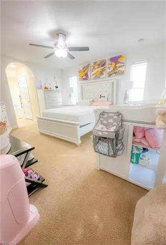 Bedroom featuring light colored carpet, multiple windows, and ceiling fan