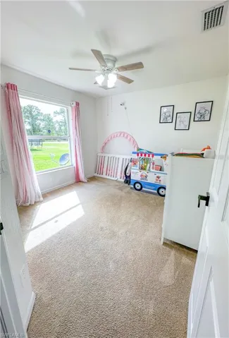 Bedroom with a crib, carpet, and ceiling fan