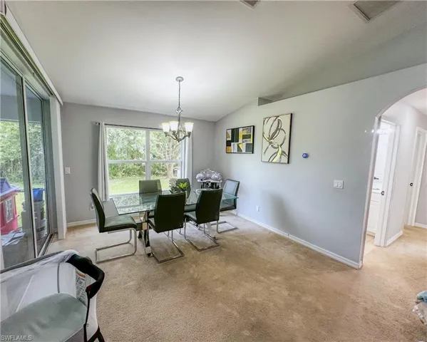 Carpeted dining area featuring an inviting chandelier and vaulted ceiling