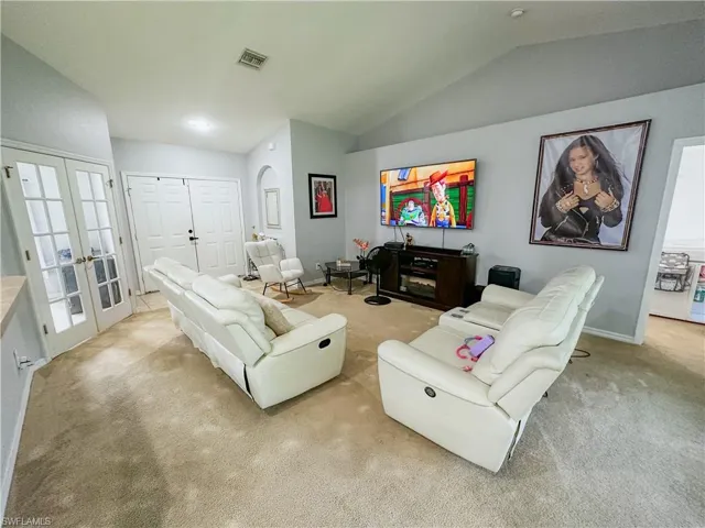 Carpeted living room featuring french doors and lofted ceiling