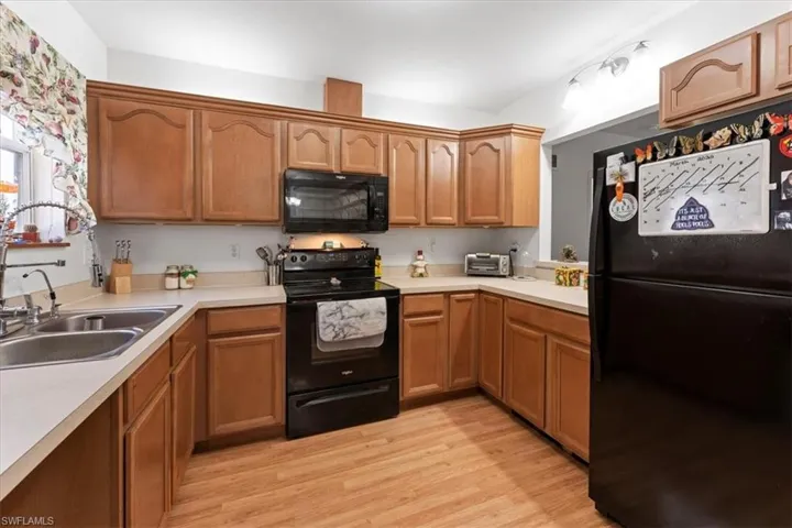 Kitchen featuring black appliances, light countertops, light wood finished floors, and a sink