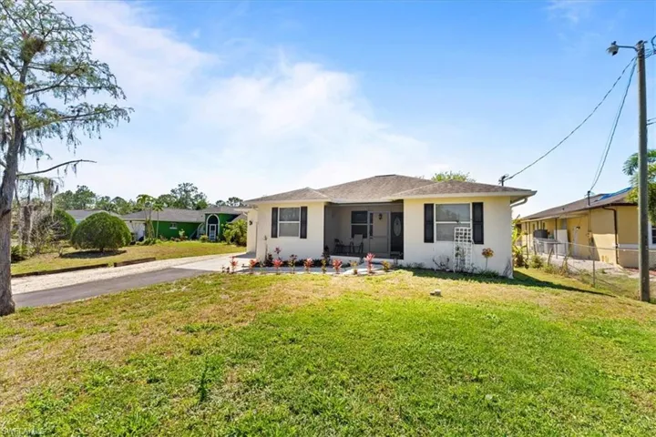 View of front of house featuring stucco siding, driveway, a front yard, and fence