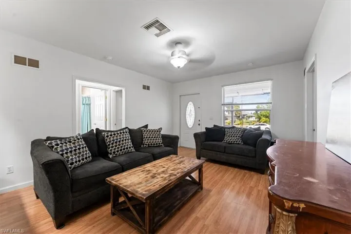 Living room with ceiling fan, visible vents, and light wood-type flooring