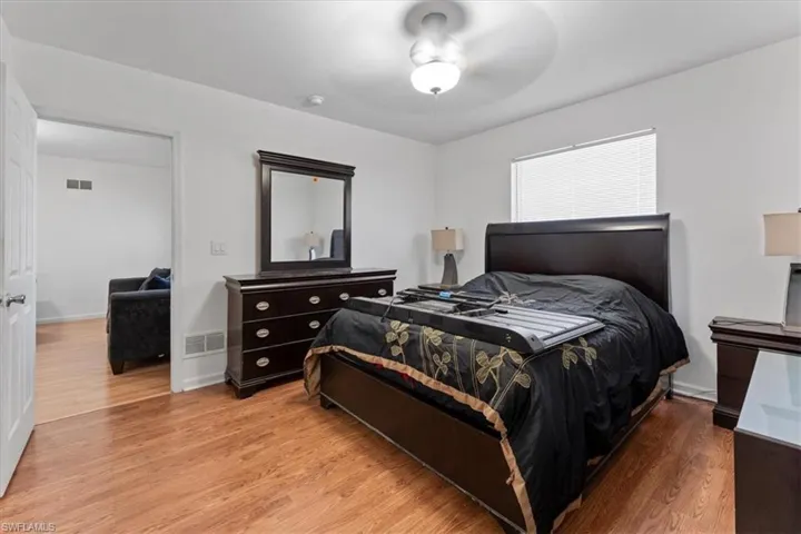 Bedroom with wood finished floors, visible vents, and ceiling fan