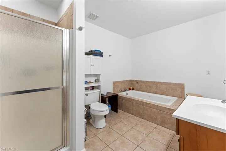 Bathroom featuring visible vents, a stall shower, a bath, tile patterned floors, and vanity