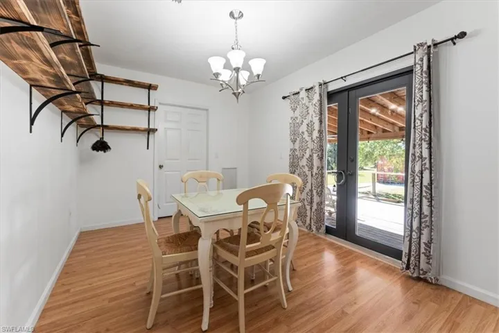 Dining space featuring french doors, baseboards, light wood-type flooring, and an inviting chandelier