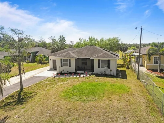 View of front facade featuring a garage, a front yard, driveway, and fence