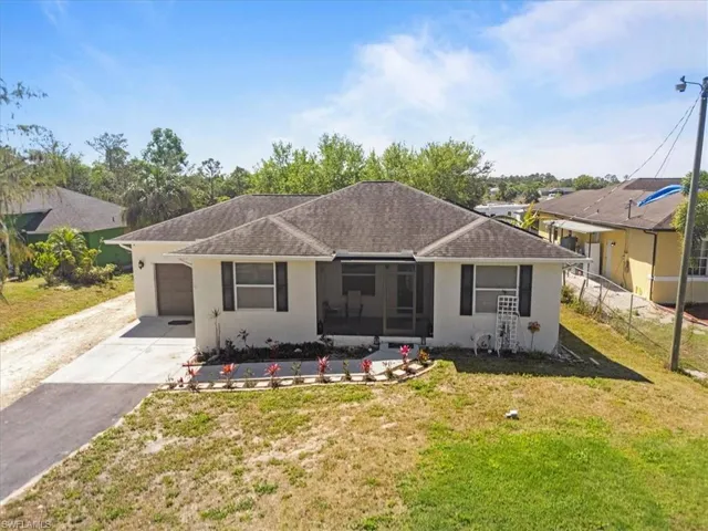View of front facade featuring a front yard, fence, driveway, stucco siding, and a garage