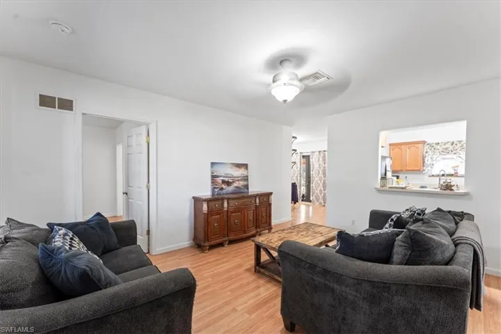 Living area with visible vents, baseboards, light wood-style floors, and ceiling fan