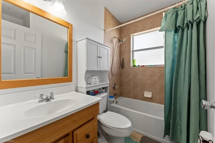 Bathroom with shower / tub combo with curtain, vanity, and toilet