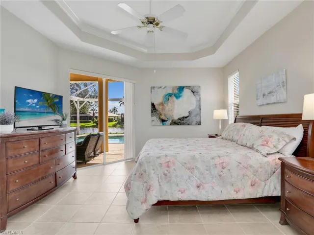 Bedroom with a raised ceiling, access to exterior, multiple windows, and crown molding