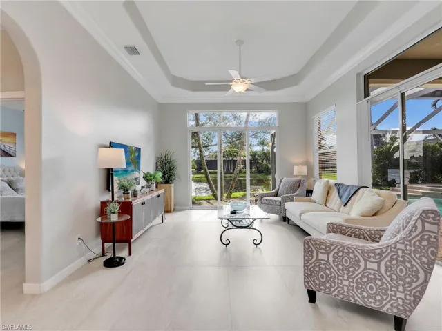 Living room featuring a ceiling fan, arched walkways, and a tray ceiling