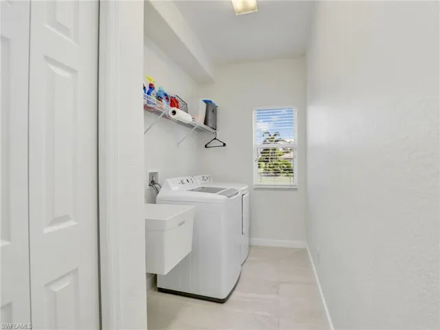 Washroom featuring washing machine and clothes dryer and baseboards