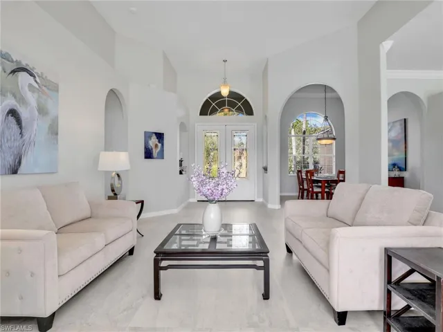 Living area with arched walkways, high vaulted ceiling, and french doors