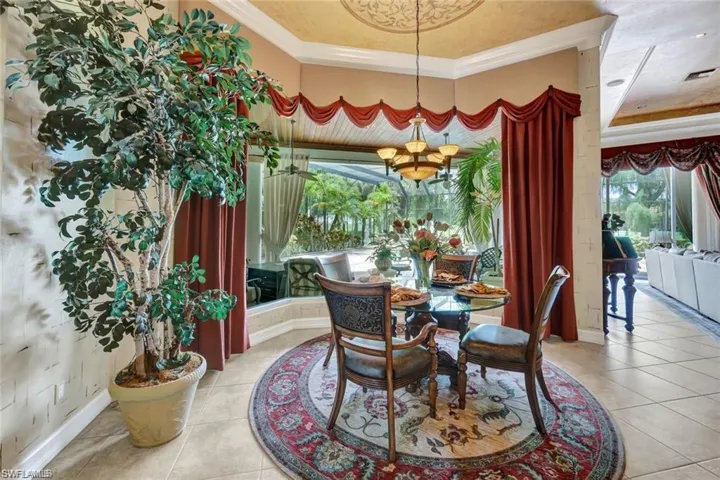 Tiled dining room with a raised ceiling, ornamental molding, and an inviting chandelier