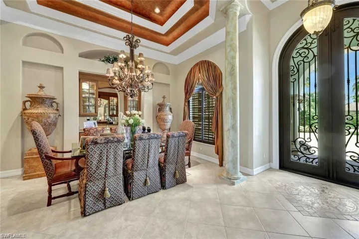 Dining space with french doors, an inviting chandelier, a raised ceiling, and ornamental molding
