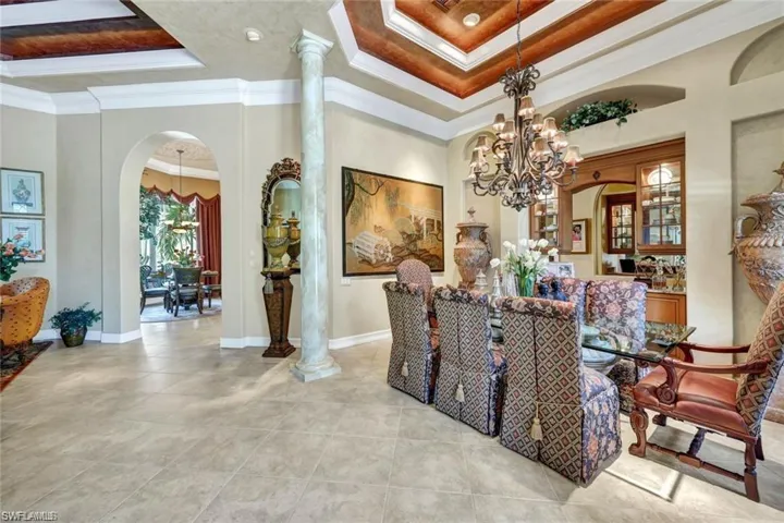 Dining space featuring a raised ceiling, crown molding, a chandelier, and a high ceiling