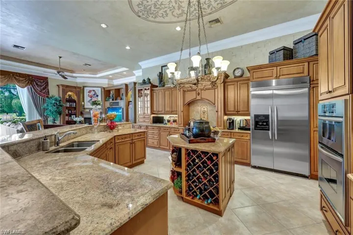 Kitchen with sink, a spacious island, decorative light fixtures, appliances with stainless steel finishes, and ornamental molding