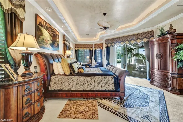 Carpeted bedroom featuring a raised ceiling, access to exterior, and crown molding
