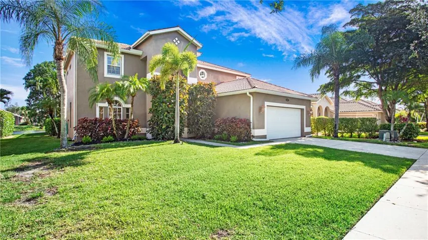 Mediterranean / spanish-style home featuring stucco siding, driveway, a front lawn, a garage, and a tile roof
