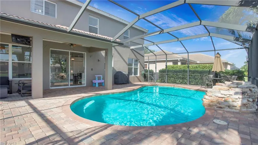 View of pool featuring a patio, ceiling fan, grilling area, and glass enclosure