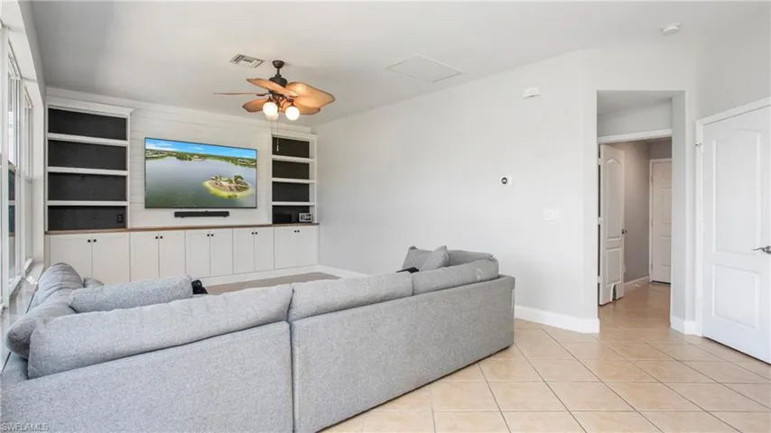Living area featuring built in features, light tile patterned floors, and ceiling fan