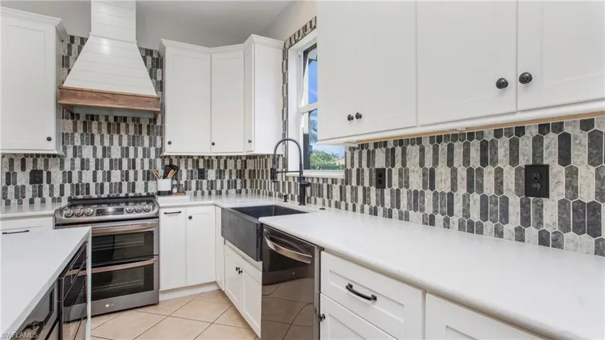 Kitchen featuring appliances with stainless steel finishes, custom exhaust hood, decorative backsplash, and white cabinets