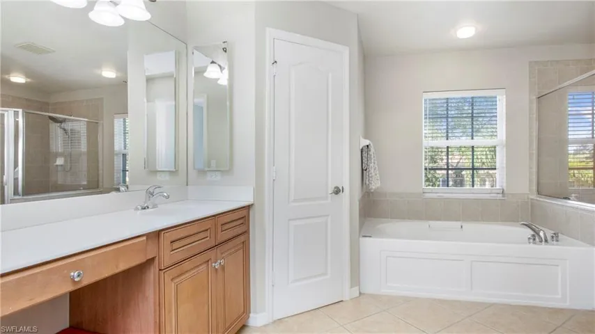 Bathroom featuring tile patterned floors, vanity, a garden tub, and a shower stall