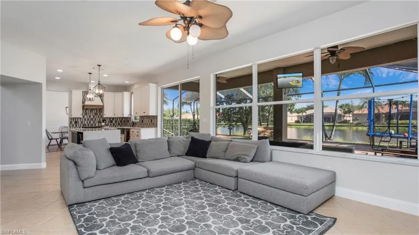 Living room with light tile patterned flooring, a ceiling fan, recessed lighting, and a chandelier