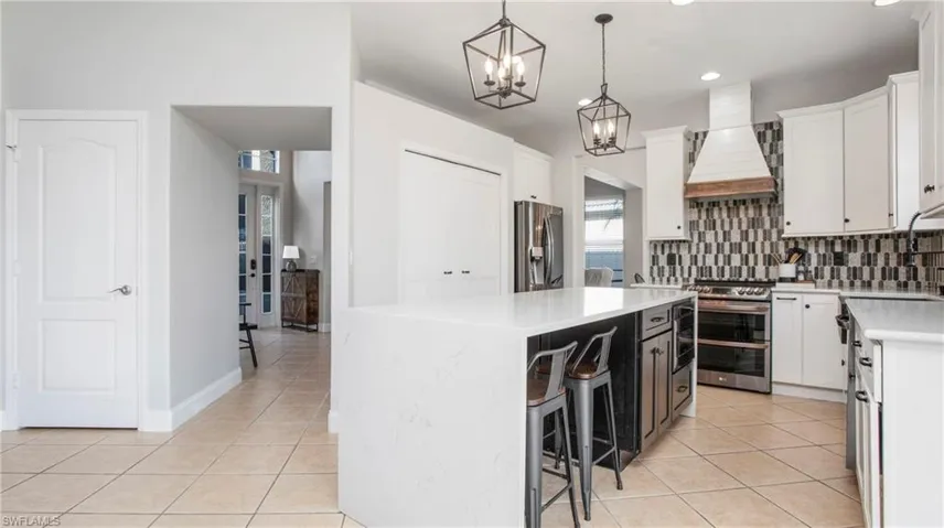 Kitchen with custom exhaust hood, stainless steel appliances, light tile patterned floors, tasteful backsplash, and recessed lighting