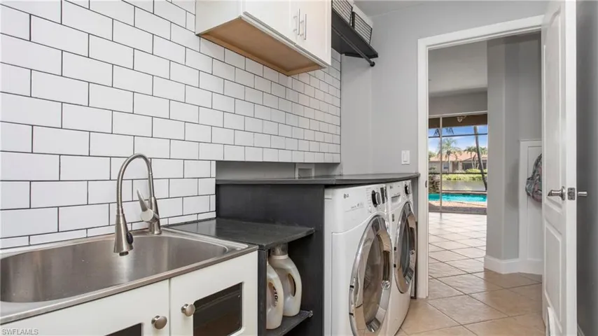 Laundry room featuring washing machine and clothes dryer, cabinet space, and light tile patterned floors