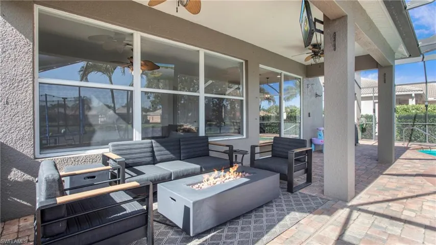 View of patio with ceiling fan and an outdoor living space with a fire pit