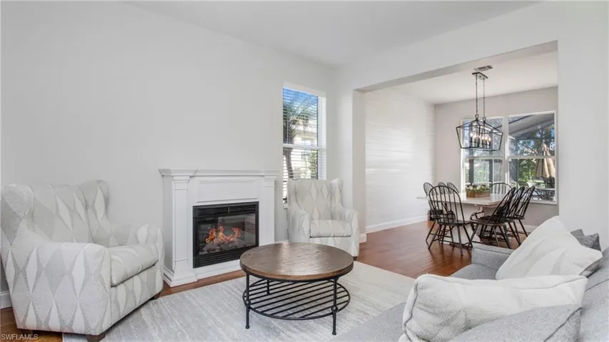 Living room featuring wood finished floors, a chandelier, and a glass covered fireplace