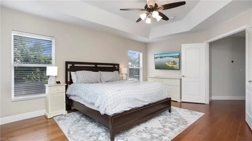 Bedroom featuring wood finished floors, a tray ceiling, and ceiling fan