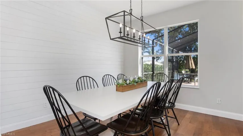 Dining space with a chandelier, dark wood-type flooring, and wood walls