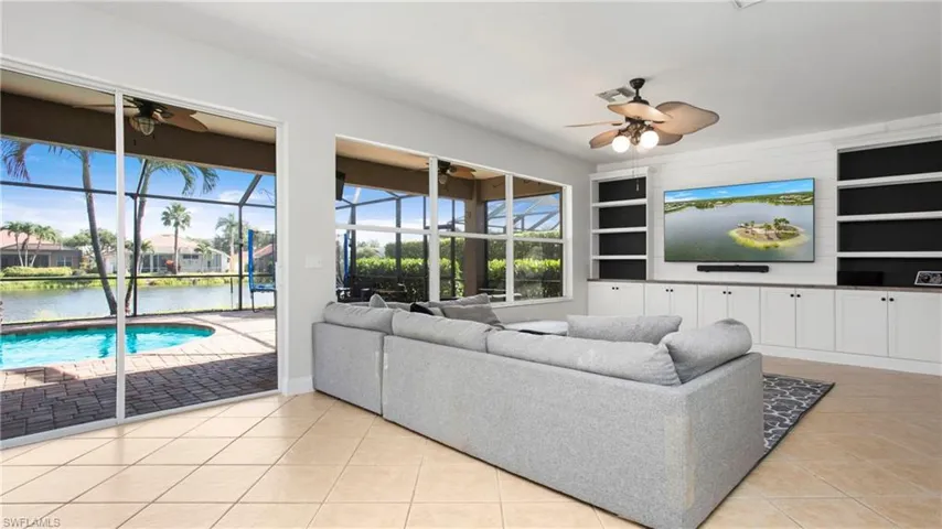 Living area with a ceiling fan, built in shelves, tile patterned flooring, and a sunroom