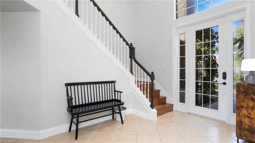 Foyer featuring stairway, light tile patterned floors, and a towering ceiling