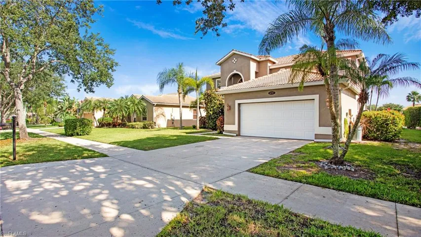 Mediterranean / spanish home featuring driveway, a garage, stucco siding, a front lawn, and a tiled roof